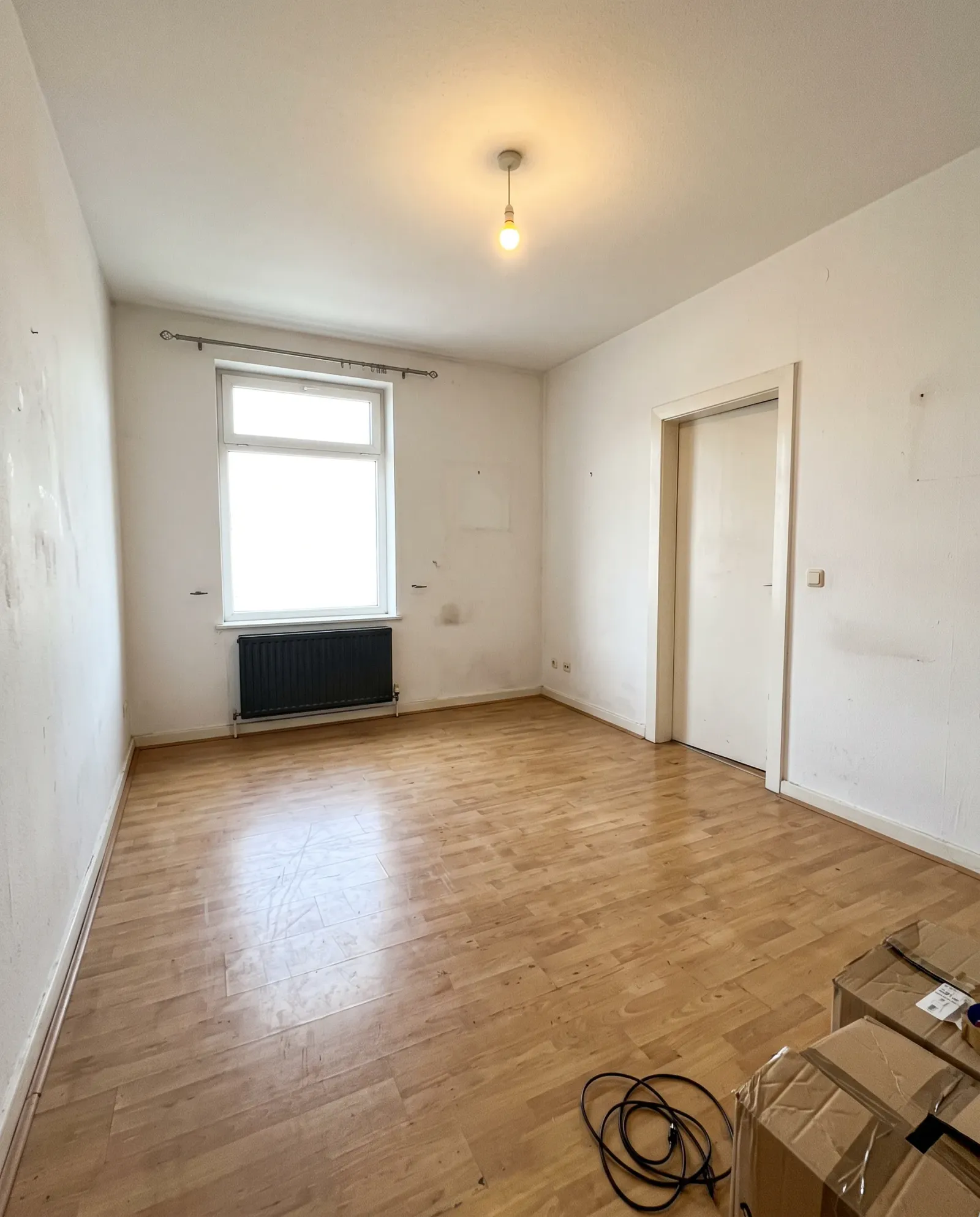 An empty white room with wooden floors and moving boxes