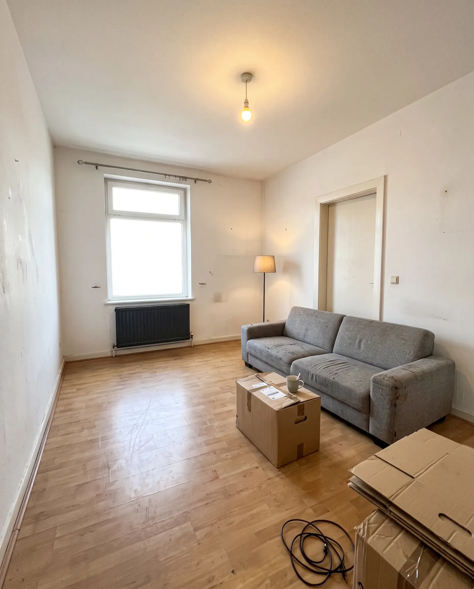 A gray sofa arrives, with boxes still on the floor
