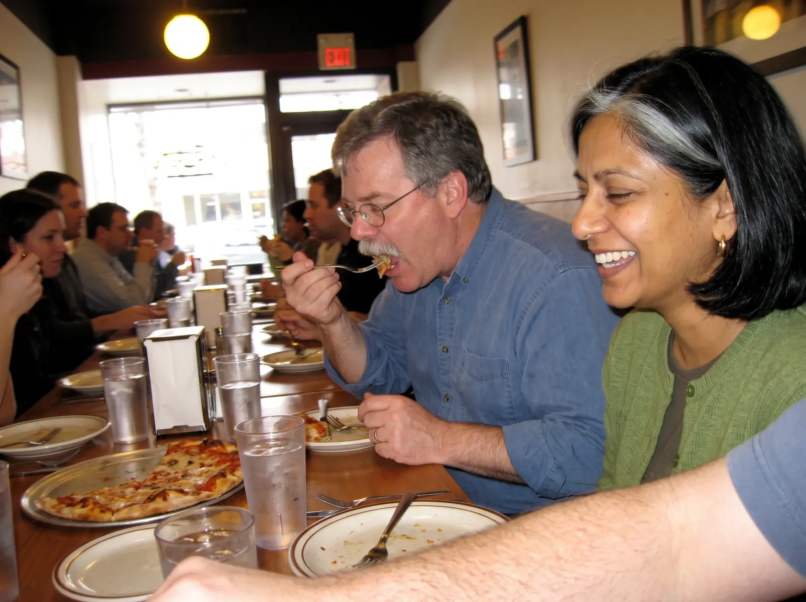 The two colleagues laughing over pizza at a team lunch